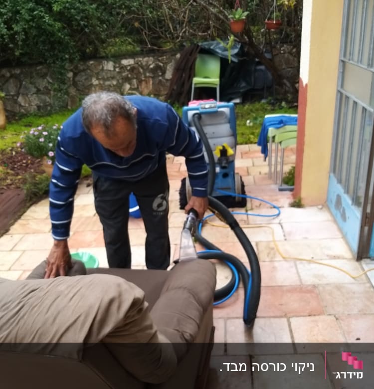 אדם מנקה ספה עם מכונת ניקוי חיצונית